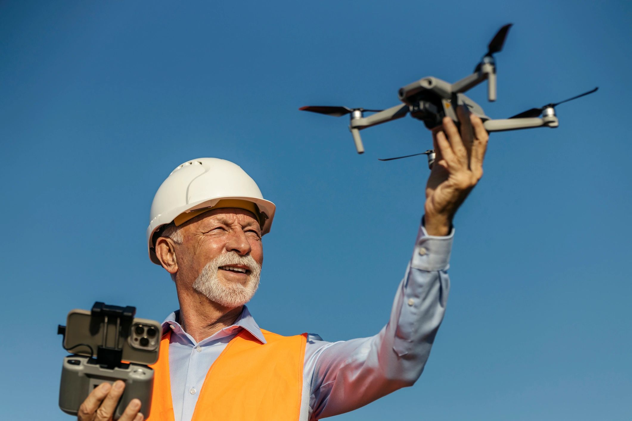 Drone pilot in safety vest operating a drone outdoors